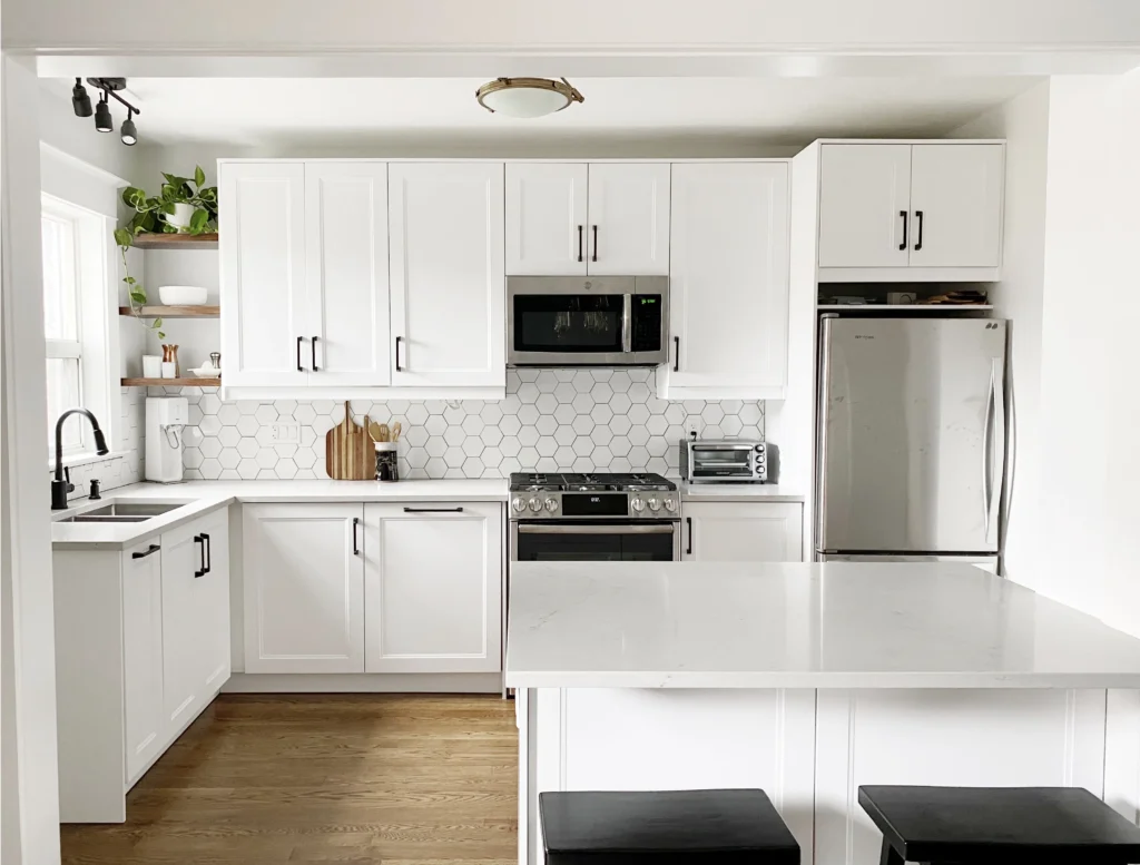 White shaker kitchen with hexagon tile backsplash and quartz island